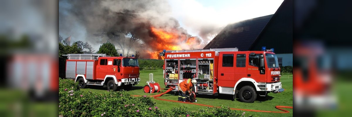 zwei Feuerwehrautos vor einem brennenden Haus