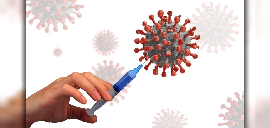 Eine Spritze wird in ein dargestelltes Corona-Virus gesteckt