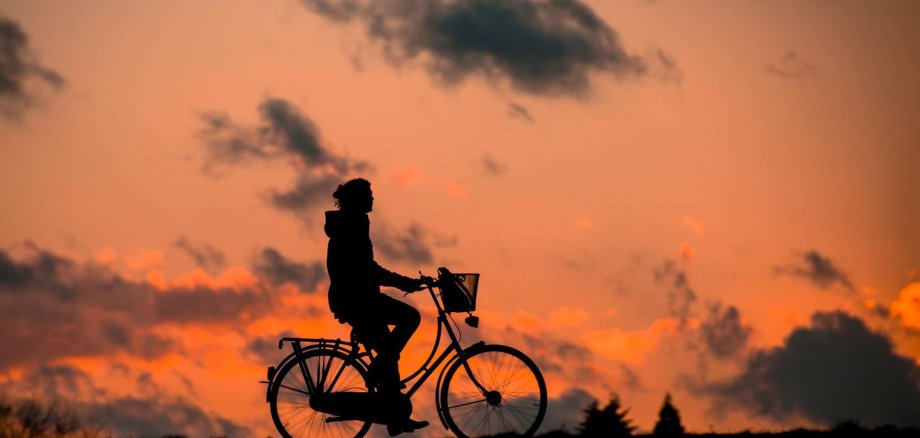 Fahrradfahrer vor der untergehenden Sonne
